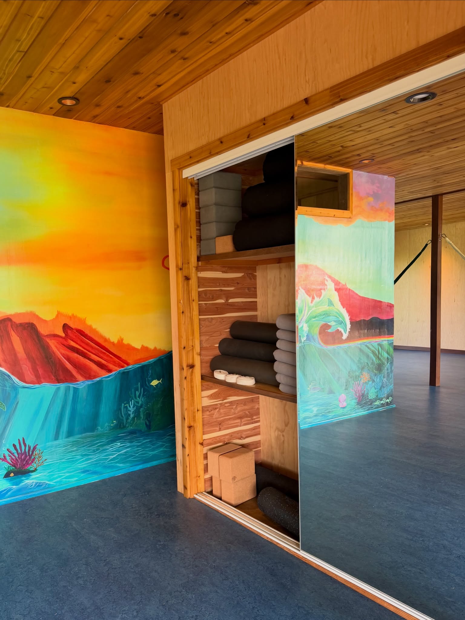 Yoga shala mural and open closet of mats, bolsters, and blankets