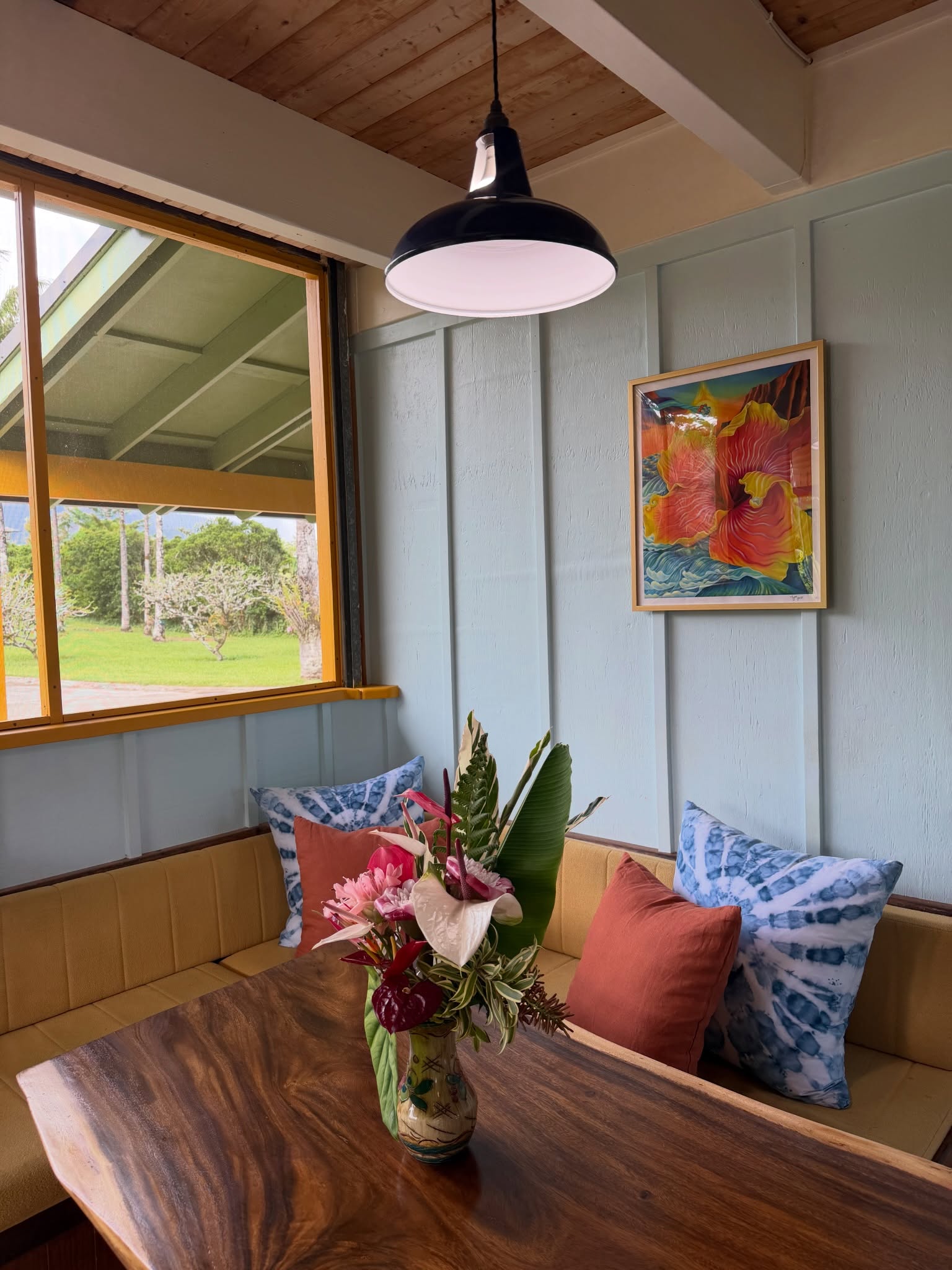 Breakfast nook with hibiscus art, flowers, and garden window