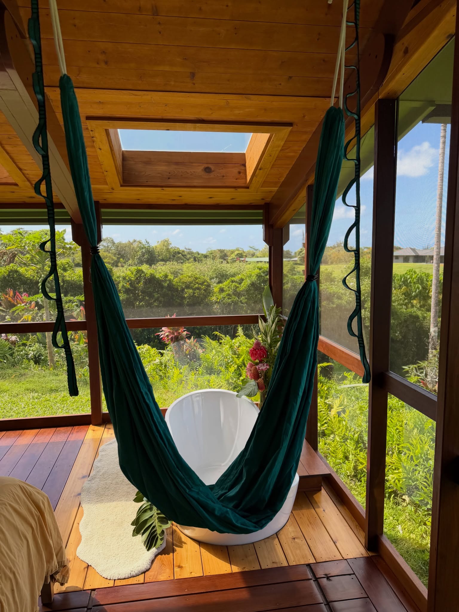 Teal hanging chair and soaking tub in a screened lanai