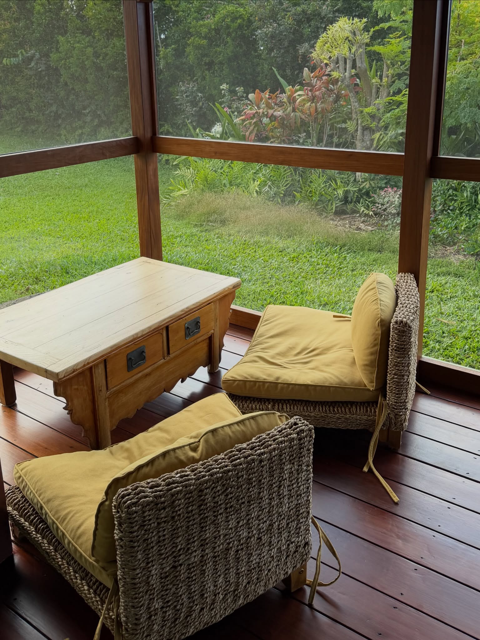 Woven chairs on the screened lanai facing the garden