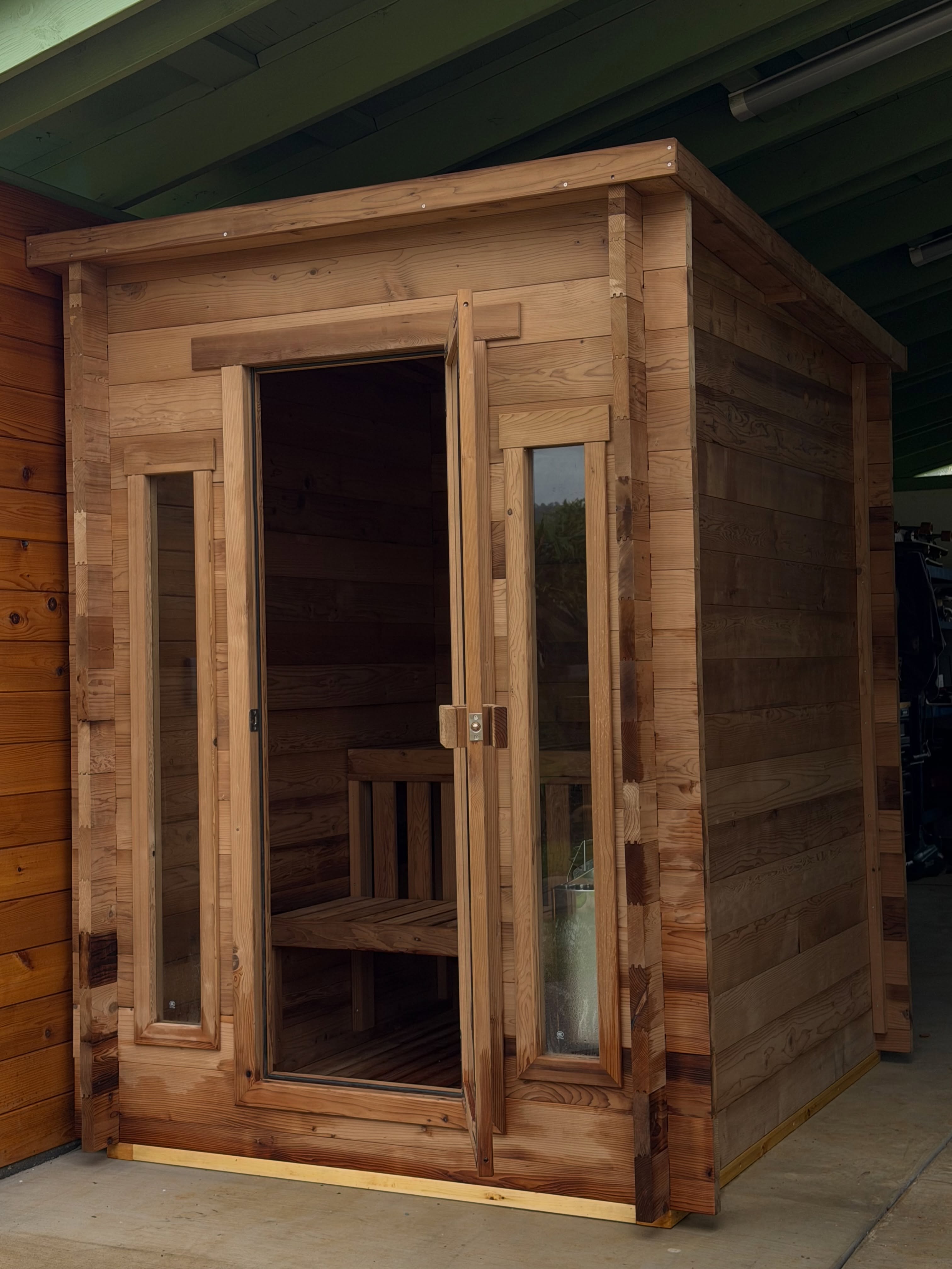 Redwood outdoor sauna with glass door on campus